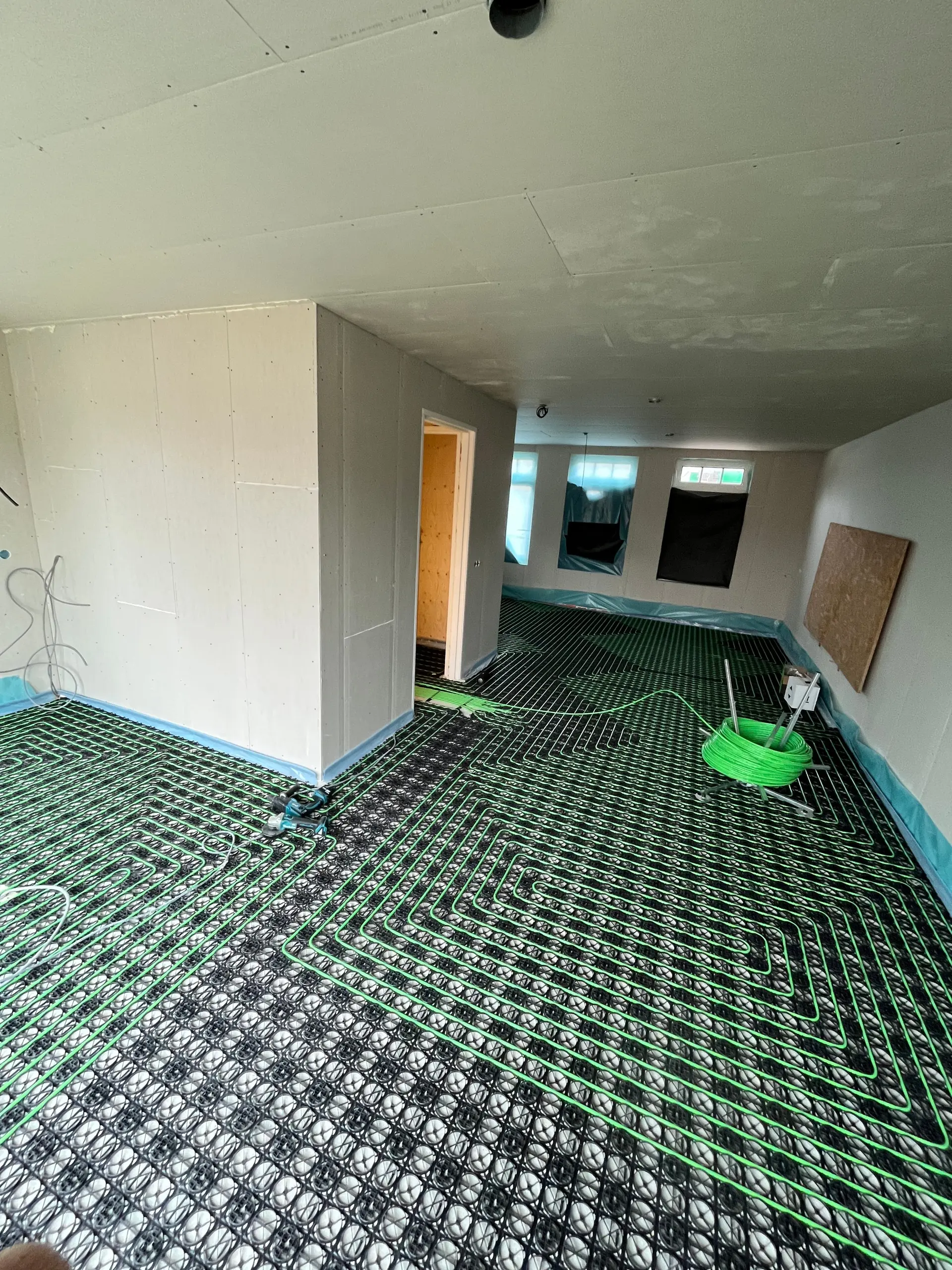 Vloerverwarmingsleiding in slakkenhuispatroon op noppenplaten, in een woning in afbouw